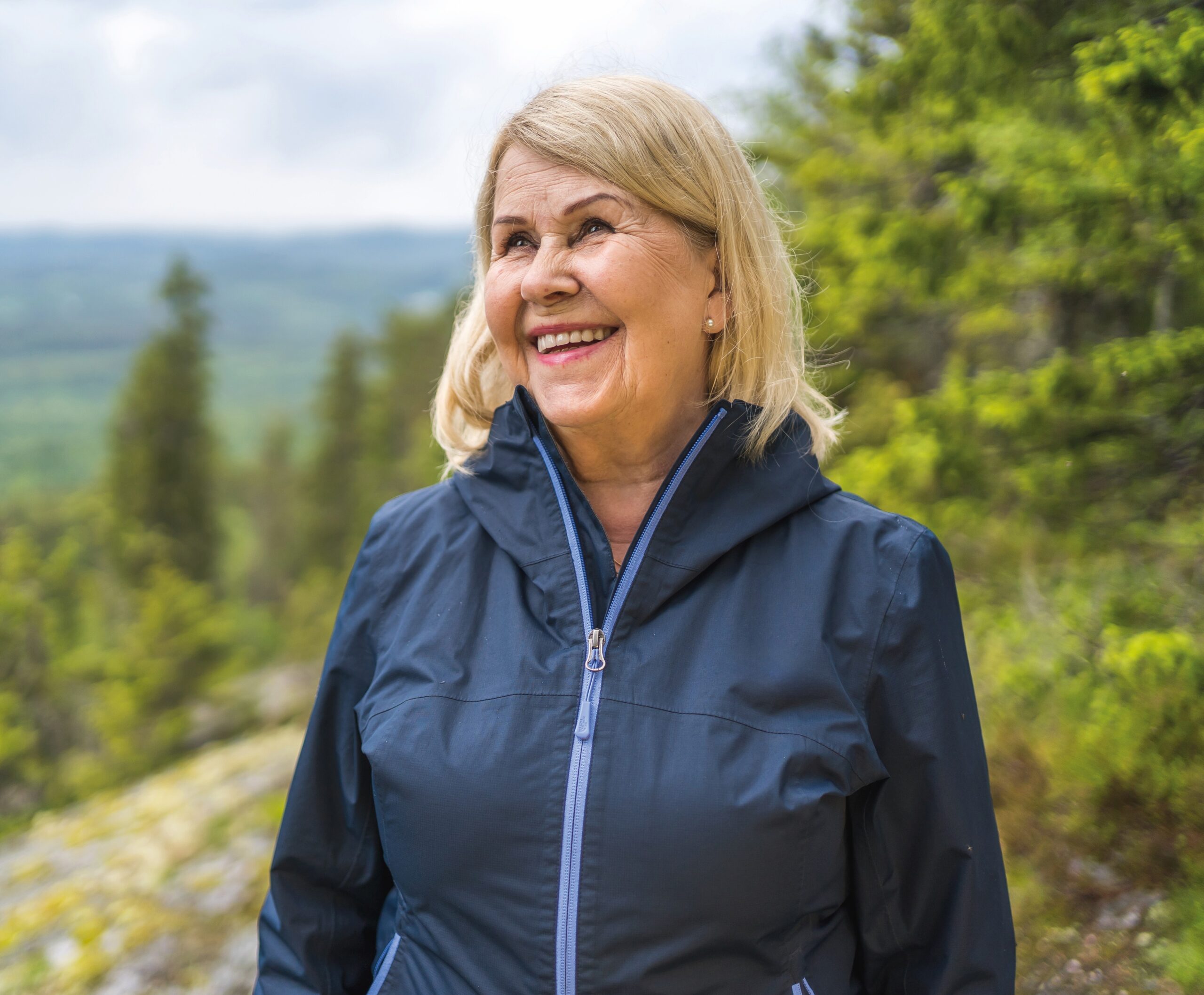 Nainen hymyilee kalliolla