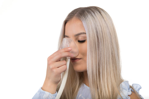 A woman using WellO2 nasal mask